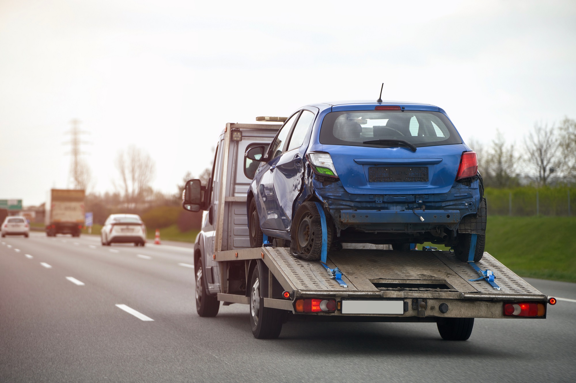 A side view of the tow truck with a damaged vehicle after being