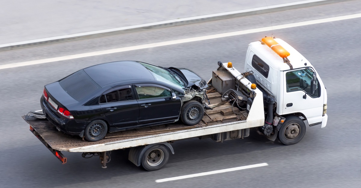 Wrecked car after an accident on a tow truck transported on a highway